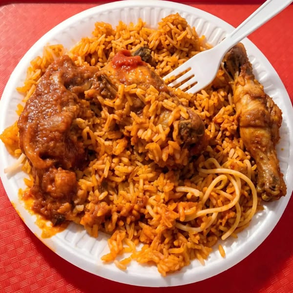 Jollof rice with chicken and spaghetti on a white plate with a plastic fork.
